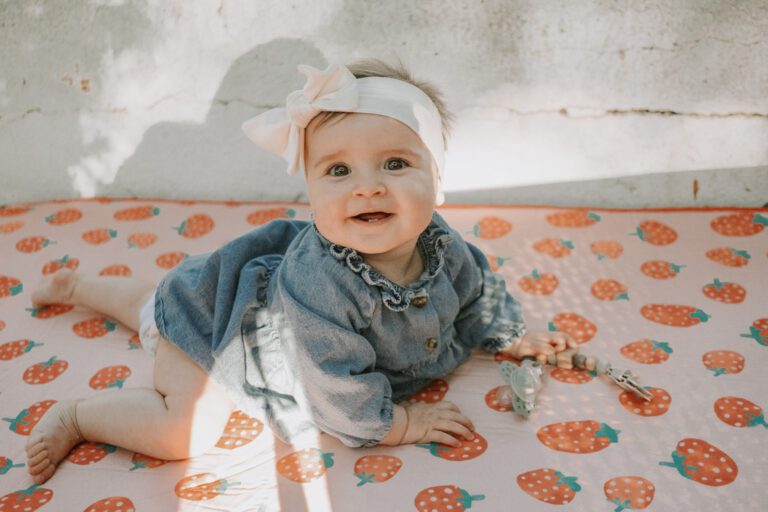 Magnifique portrait de bébé éveillé qui rampe sur son tapis aux motifs fraise lors d'un mariage.